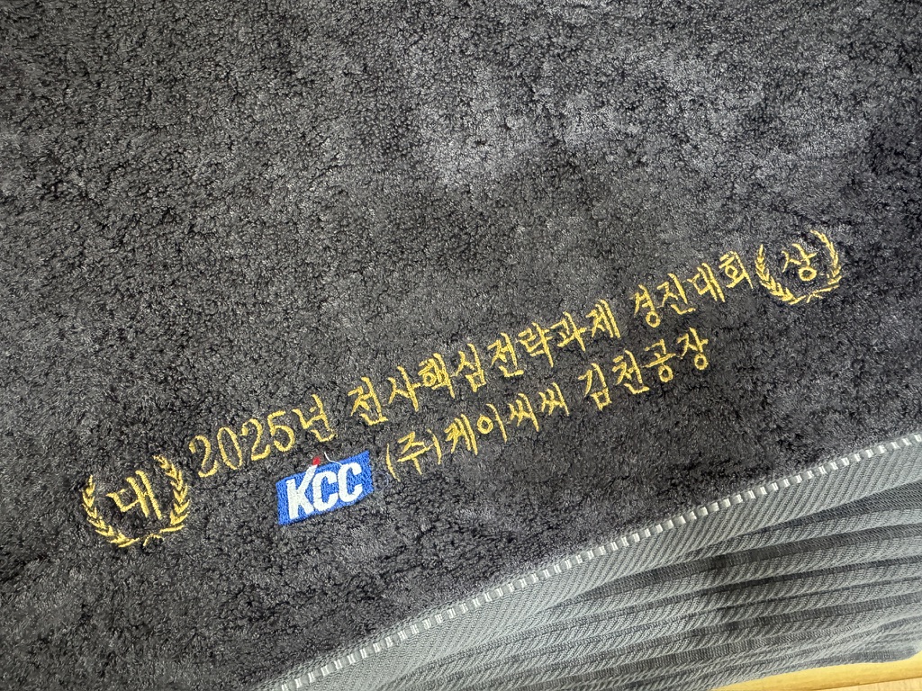 짙은 회색 타월에 KCC 로고와 수상 기념 문구를 자수한 실제 사진